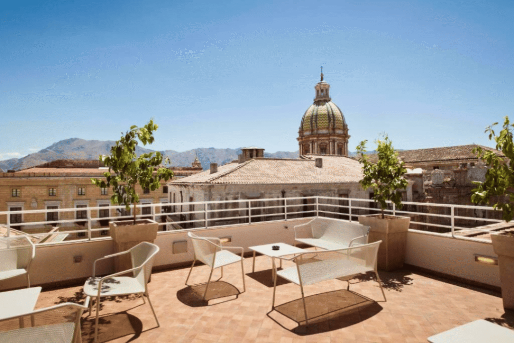 Stühle und Tische auf der Dachterrasse eines Hotels in Palermo