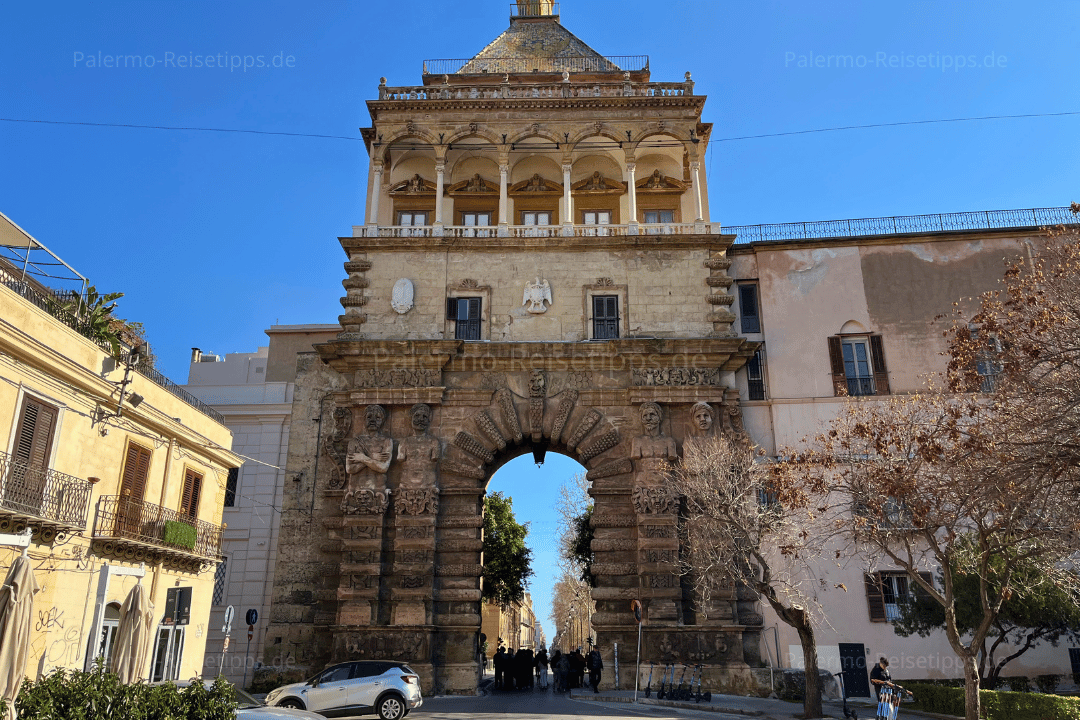 Autos und Menschen vor einem steinernen Stadttor in Palermo