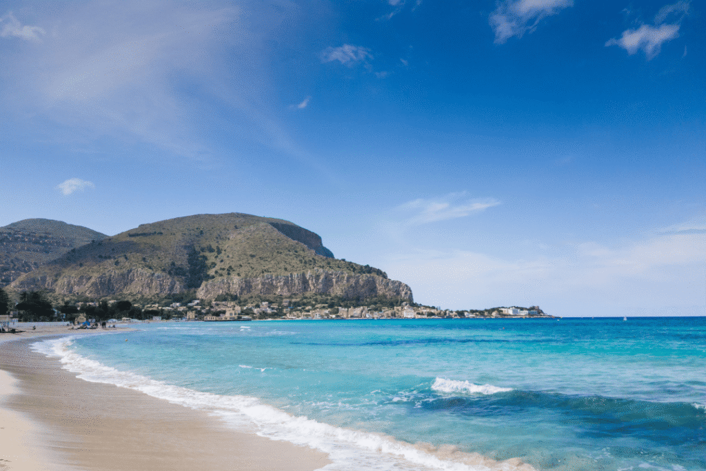 Sandstrand und Meer mit Bergen im Hintergrund